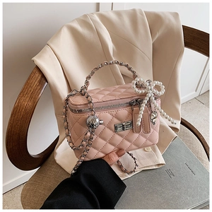 Detail view of pink quilted box bag with pearl bow and silver chain strap