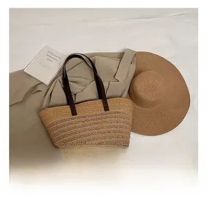 Flat lay of straw tote bag with leather straps, sun hat, and blazer in a French vacation style