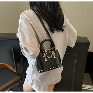 Elegante borsa a mano nera con borchie dorate e tracolla a catena indossata da una modella