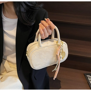 Detailansicht der cremefarbenen Boston Bag mit Prägung und Tennis-Schläger-Anhänger-Dekor