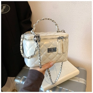 Detailed close-up of quilted white handbag with silver chain and leather-wrapped handle