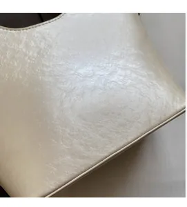 Détail de la texture en cuir PU crème doux et du logo doré embossé sur le sac à main