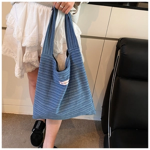 Detail of blue striped tote bag featuring a 'have a nice day' pink patch design