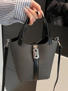 Minimalist black textured bucket bag with silver hardware and leather handles in hand