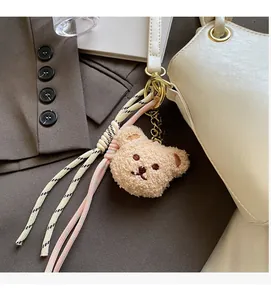 Détail d'une breloque ours en peluche avec sangle tissée sur un sac à main blanc