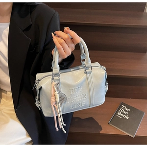 Detail of light blue faux leather bowling bag with embossed lettering and woven charm