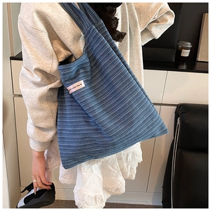 Detailed macro view of the blue knitted tote bag showing ribbed texture and pink label