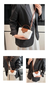 Detail view of mini nylon crossbody bag with brown leather handles and gold metal snap fastener