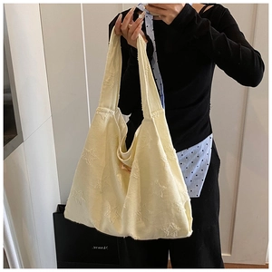Detailed close-up of cream canvas tote bag with 3D star jacquard texture and wide strap