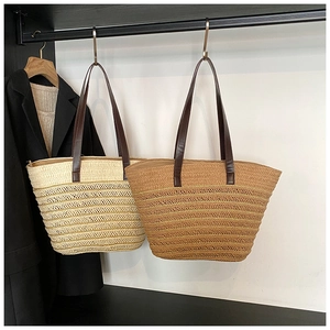 Detail of hand-woven straw tote bags in beige and light brown with leather straps