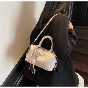 Close-up of cream soft leather bowling bag with tennis charm and embossed detail
