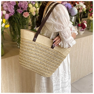 Detail view of woven straw tote bag with contrast leather straps in a floral shop