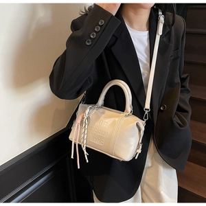 Detail of off-white retro bowling bag with letter embossing and decorative rope knot