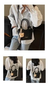 Détail du sac seau noir en similicuir avec logo doré, anneau métallique et charme d'ours