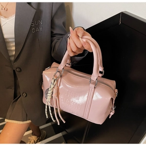 Detailed macro view of pink patent leather handbag with embossed letters and woven tassels