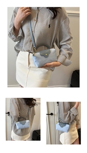 Detail view of the contrast-color dumpling tote bag with leather flap and gold hardware