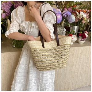 Straw woven tote bag with golden wave pattern and brown leather straps for summer vacation