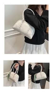 Détail du sac à bandoulière en similicuir blanc avec tressage décoratif et logo embossé