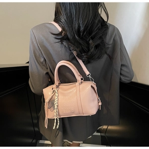 Detail of pink faux leather bowling bag with letter embossing and braided charm