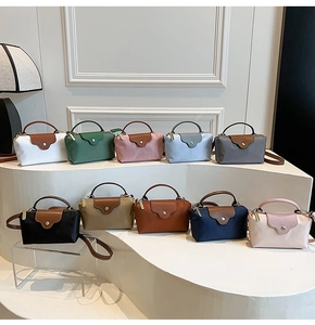 Detail of colorful mini crossbody bags with leather handles on a minimalist display