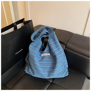 Detailed shot of blue corduroy tote bag with 'have a nice day' label on leather seat