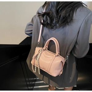 Detail of pink leather Boston bag featuring embossed text and woven rope charm