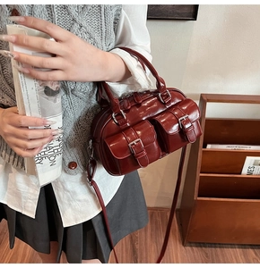 Gros plan du sac Boston vintage en cuir ciré bordeaux avec poches avant décoratives