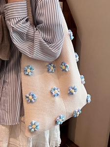 Sac fourre-tout beige en maille avec fleurs au crochet porté à l'épaule par un mannequin