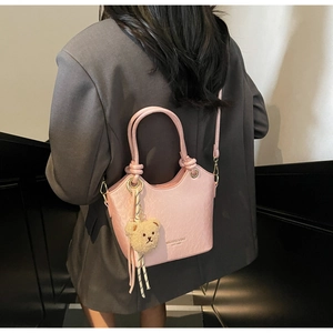 Détail du sac seau en cuir PU rose avec quincaillerie dorée et charm ours en peluche