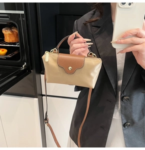 Close-up of contrast leather trapezoid bag with gold hardware and top handle detail