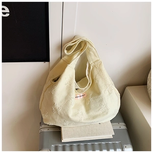Detail of cream canvas tote bag with embossed star patterns and pink brand label
