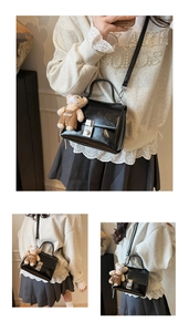 Detail of black glossy leather crossbody bag featuring silver lock and cute bear charm