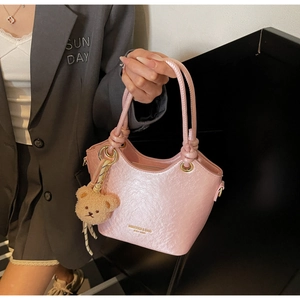 Détail du sac seau en cuir rose pâle avec un joli pendentif ours brun en peluche