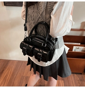 Vue détaillée du sac Boston en cuir noir brillant avec boucles et poches argentées
