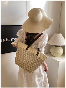 Close-up of woven straw tote bag with brown leather handles and sharp texture detail