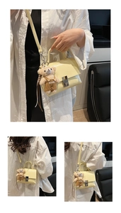 Detail of light yellow retro square handbag with metallic lock and cute bear charm