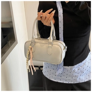 Sac bowling chic gris clair avec pendentif tissé porté à la main par un mannequin
