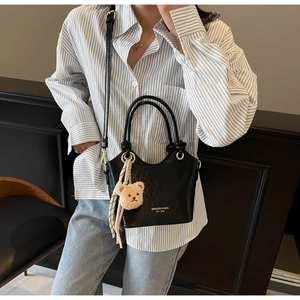 Détail du sac seau noir en PU avec breloque ours en peluche et ruban à rayures