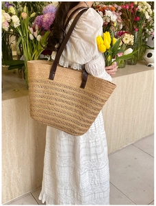Detail of hand-woven straw tote with leather straps and golden wavy hollow-out pattern