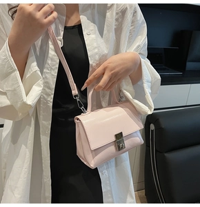 Detail of light pink leather crossbody bag with silver metal lock and top handle