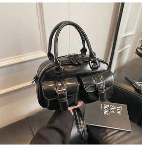 Détail du sac Boston noir en cuir huilé avec deux poches avant à boucle et poignée robuste