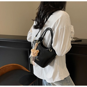 Détail du sac seau noir en cuir PU avec garnitures dorées et pendentif ours en peluche