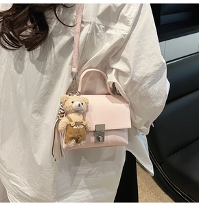 Detailed side view of pink crossbody bag with metal twist lock and cute bear charm