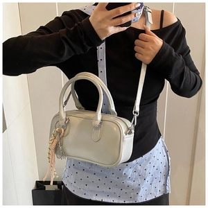 Selfie miroir montrant un sac à main Boston crème avec poignées et pompons