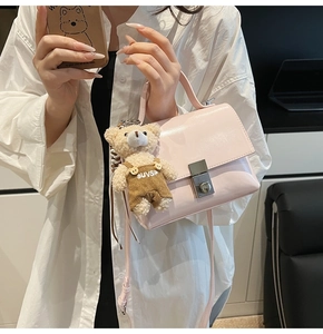 Detail of light pink patent leather handbag with silver twist lock and bear charm