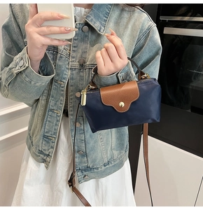 Close-up of contrast color mini nylon handbag with leather flap and gold ring buckle