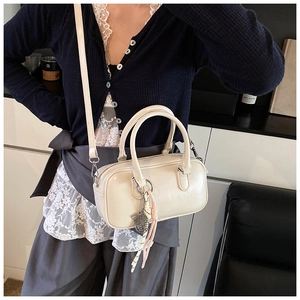 Détail du sac bowling crème avec pendentif en maille argentée et sangle tressée