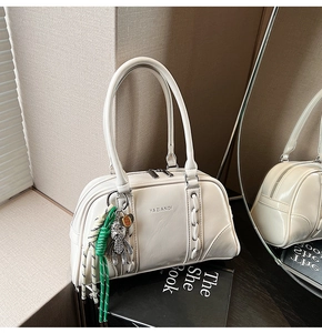 Détail du sac Boston beige avec logo YAZIANDI, côté tressé et charm d'ours métallique