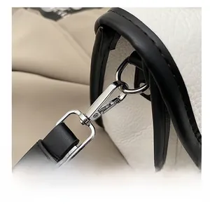 Close-up of premium chrome metal buckle on white lychee grain leather messenger bag