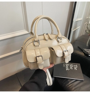 Détail du sac Boston en cuir beige ciré avec deux poches à boucle sur le devant